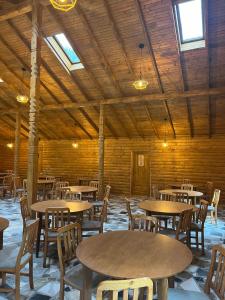 a room with wooden tables and chairs and windows at Satul de vacanta Cuibul Lupilor in Ciucea