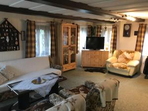 a living room with a couch and chairs and a tv at Roubenka Na vršku in Staré Křečany
