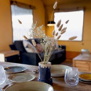 a table with plates and a vase with dried flowers at The Camp at The Wave in Bristol