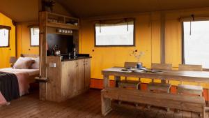 a room with a table and a bed and yellow walls at The Camp at The Wave in Bristol