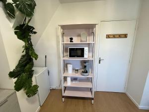 a room with a shelf with a microwave and a tv at L Atelier du Centre in Vendôme +7 photos