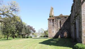 an old stone building with a grassy yard with trees at La Solitude in Bois-de-Cené
