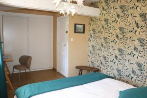 a bedroom with a bed with a blue and white wallpaper at La Solitude in Bois-de-Cené