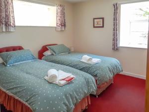 two beds with towels on them in a bedroom at Ivy Cottage in Mountblairy +2 photos