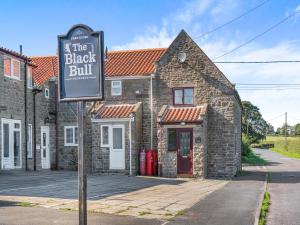 a sign for the black bill in front of a brick building at Black Bull Cottage in Ugthorpe