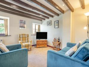 a living room with two blue couches and a tv at Black Bull Cottage in Ugthorpe +14 photos