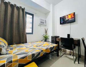 a bedroom with a bed and a desk and a tv at Tower1 Smdc green2 Dasmarinas in Dasmariñas