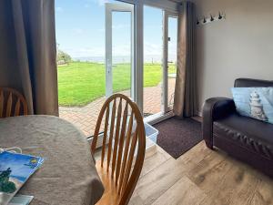 a living room with a table and a couch and a window at No 1 Hickling Chalet - Uk51726 in Scratby