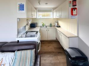 a small kitchen with white cabinets and a stove at No 1 Hickling Chalet - Uk51726 in Scratby