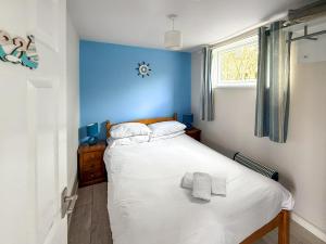 a bedroom with a white bed with a blue wall at No 1 Hickling Chalet - Uk51726 in Scratby