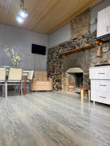 a living room with a stone fireplace and a table and chairs at racha cozy cottage in Ambrolauri