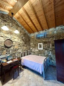 a bedroom with a bed and a table in a stone wall at Agroktima Konstantinos & Eleni in Platy