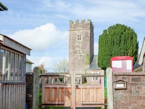 a gate in front of a building with a tower at Welcome Cottage in Woolfardisworthy
