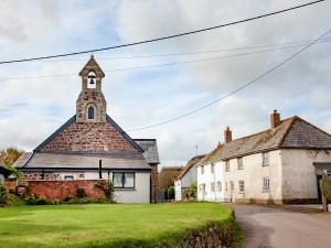 an old building with a clock tower on a street at Welcome Cottage in Woolfardisworthy