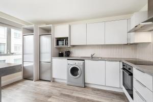 a kitchen with white cabinets and a washer and dryer at Canvas Mayor Square in Dublin