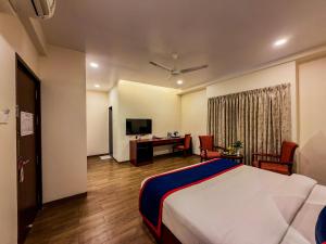 a bedroom with a bed and a desk with a computer at Zip By Spree Hotels Kolhapur in Kolhapur