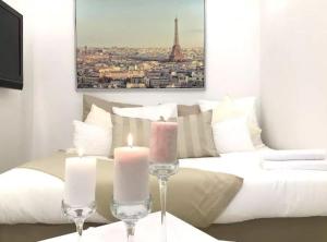 a bedroom with a white bed with two candles at Appartements Haussman Lafayettes in Paris