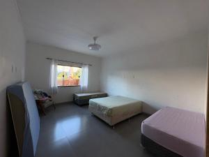 a small room with two beds and a window at Recanto Gil Viana in Pouso Alegre