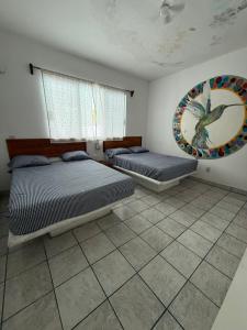 a bedroom with two beds and a painting on the wall at Casa de las Iguanas Tecolutla in Tecolutla +3 photos