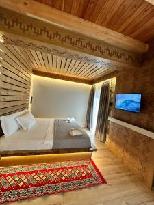 a bedroom with a bed and a tv on a wall at Golden Villa in Theth