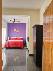 a bedroom with a red bed with a purple wall at The Prime Residences of Samuels Comfort Homes in Bangalore
