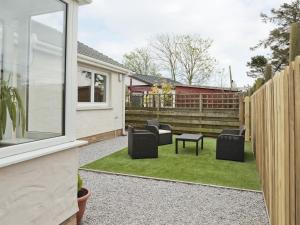 a patio with chairs and a table and a fence at Firth Lodge in Mainsriddle