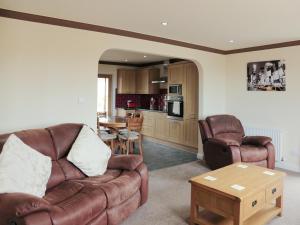 a living room with a couch and chairs and a table at Firth Lodge in Mainsriddle