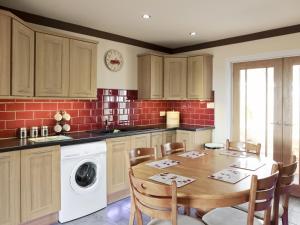 a kitchen with a table and a washing machine at Firth Lodge in Mainsriddle +3 photos
