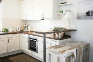 a kitchen with white cabinets and a table and stool at Ferienhaus Dwarslöper mit Sauna und Garten in Fuhlendorf in Fuhlendorf