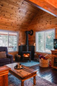 a living room with a fireplace in a cabin at Repère de la Rivière - Bord de l'eau- Activités nautiques in Saint-Alexis-des-Monts