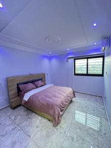 a bedroom with a bed with purple walls and a window at Egel appartement in Yaoundé