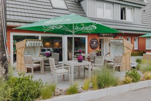 a table with a green umbrella in front of a restaurant at Lagune No1 in Büsum