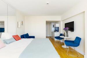 a bedroom with a large white bed and blue chairs at Orbi HighView Panoram Hotel in Batumi