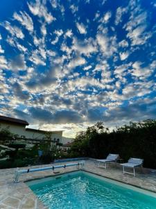 a swimming pool with a cloudy sky above it at Villa Basilicata in Pedale
