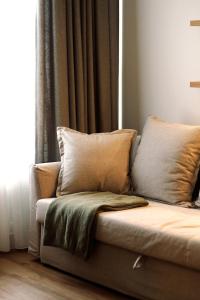 a couch with pillows in a room with a window at Not A Hotel Cesis in Cēsis