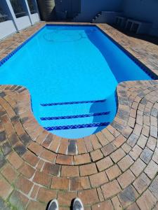 a swimming pool with blue water and a pair of shoes at Unit 5 in Serengeti Complex, Bloemhof, Bellville in Blomtuin