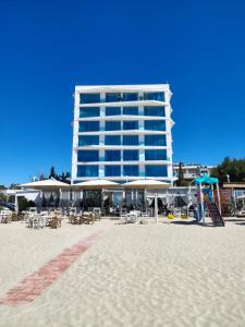 a building on the beach with chairs and tables at All Seasons Apartment in Durrës