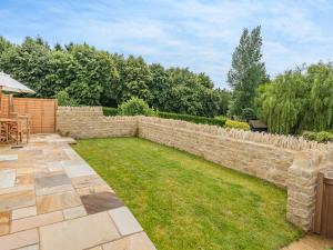 a garden with a stone retaining wall and grass at The Mill Lodge in Malmesbury