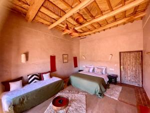 a bedroom with two beds and a wooden ceiling at Maison d'hôtes de charme Kasbah de Mimi Gorges du Dades in Aït Yous +129 photos