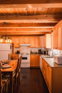 a kitchen with wooden cabinets and a wooden table at Repère de la Rivière - Bord de l'eau- Activités nautiques in Saint-Alexis-des-Monts