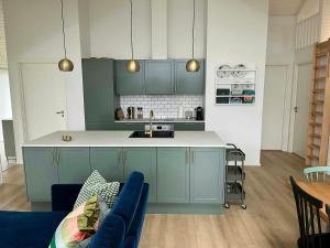 a kitchen with blue cabinets and a blue couch at Modern House In Second Row At Rude Strand in Odder