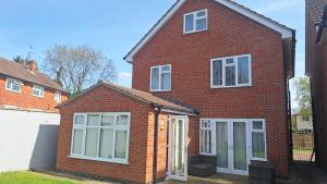 a red brick house with white windows and doors at Modern spacious private detached house in Beeston