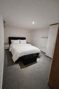 a bedroom with a large bed with white sheets and pillows at Spacious 2BR with ensuite and AC unit and balcony near Heathrow in Cranford