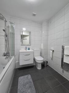 a bathroom with a toilet and a sink and a tub at Spacious 2BR with ensuite and AC unit and balcony near Heathrow in Cranford +12 photos