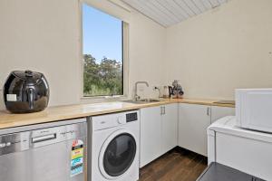 a kitchen with a washing machine and a window at Tiny house at Gilderoy Valley Views in Yarra Junction