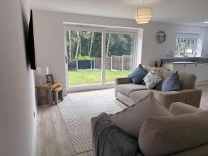 a living room with two couches and a kitchen at Low Street Escape 3 Bed, Sleeps 9, Gated Drive, WiFi, Contractors in Great Wyrley