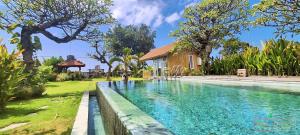a swimming pool in front of a house at Rumah Putih Beachfront Bungalow in Tegallengah