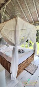 a bed in a room with a mosquito net at Rumah Putih Beachfront Bungalow in Tegallengah