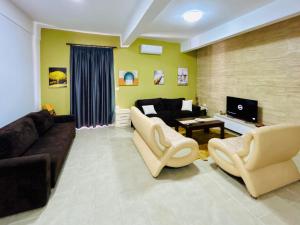 a living room with a couch and chairs and a tv at Kristian apartments in Berat