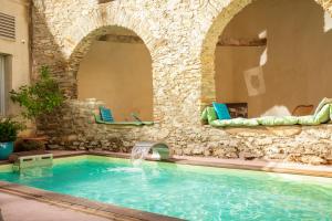 a pool with a stone wall and a water fountain at Château De Siran - Hôtel & Spa in Siran